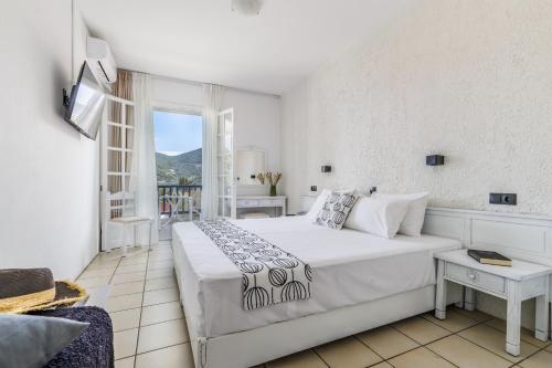 a white bedroom with a large bed and a window at Aperitton Hotel in Skopelos Town