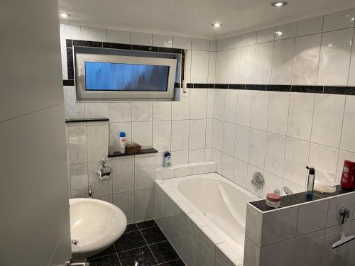 a bathroom with a tub and a sink and a tv at Wohnung direkt am Wald in Warstein