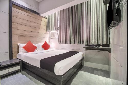 um quarto com uma cama com almofadas vermelhas em Capital O 75709 Hotel Spring Residency em Mumbai