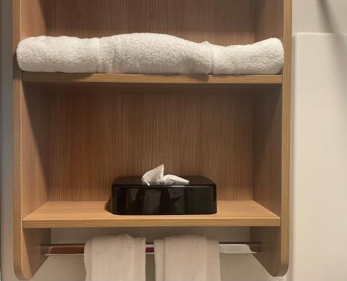 a wooden cabinet with a black box and towels at Microtel Inn & Suites by Wyndham Liberty NE Kansas City Area in Liberty