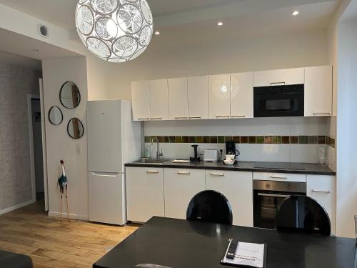 uma cozinha com armários brancos e uma mesa preta em Suite & Lake - Proche du Lac d'Annecy em Annecy