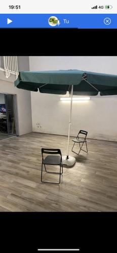 una stanza con due sedie e un ombrellone verde di SMAC ad Andria