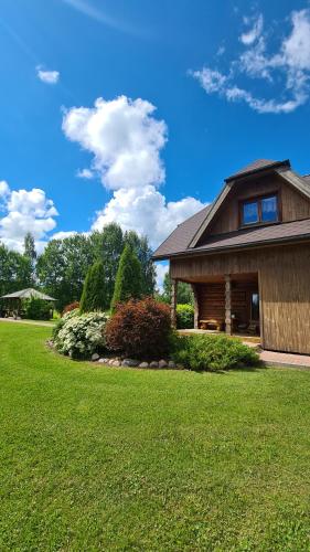 una casa con un patio verde con un edificio en Trīssaliņas, en Aumeisteri