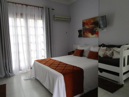 a bedroom with a white bed and a window at Ilha flat Hotel Suíte Swaenen II in Ilhabela