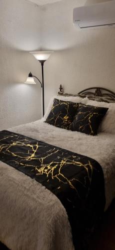 una cama con una manta negra y dorada y una lámpara en Bonito Loft Capri, 5 m Consulado en Ciudad Juárez