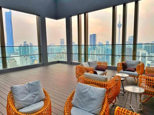uma varanda com cadeiras de vime, mesas e janelas em Axon Residence Bukit Bintang By TR Suites em Kuala Lumpur