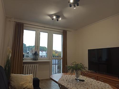a living room with a flat screen tv and a table at APARTAMENT CENTRUM Międzychód in Międzychód
