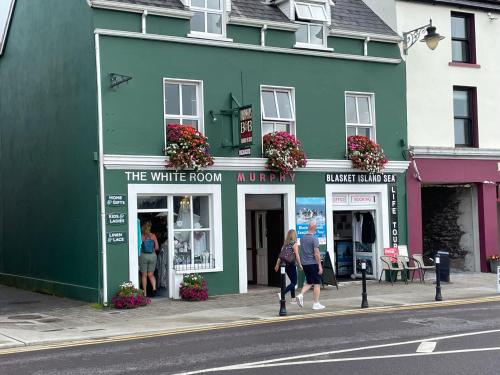 a green building on a street with people walking in front at Murphy's Guesthouse in Dingle