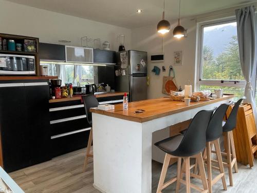 eine Küche mit einer Theke und Stühlen in der Unterkunft Casa moderna en el bosque y montaña in Villa La Angostura