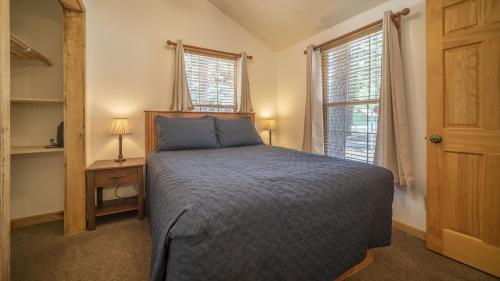 1 dormitorio con 1 cama, escritorio y 2 ventanas en The Iris Cabin #1 at Blue Spruce RV Park & Cabins, en Tuckerville