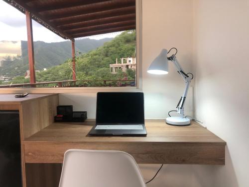 a laptop computer sitting on a wooden desk with a window at Cabañas Annapurna in Taganga