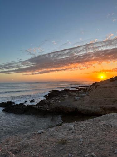 a sunset over the ocean with a rocky beach at Chill House surf camp in Sidi Kaouki