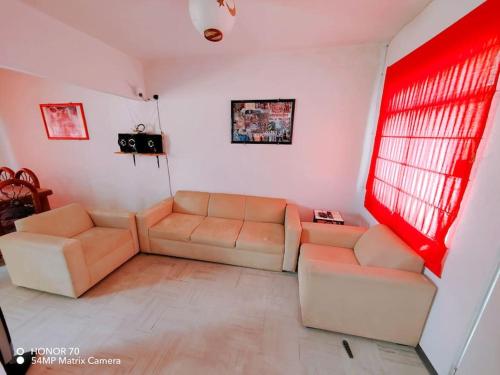 a living room with two couches and a red window at Hermosa casa a un paso del mar! in La Sabana