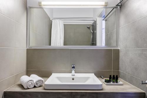 een badkamer met een wastafel en een spiegel bij Aperitton Hotel in Skopelos Town