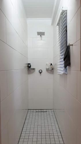 La salle de bains est pourvue de carrelage blanc, d'une douche et d'une fenêtre. dans l'établissement Our Happy Place, à Natureʼs Valley