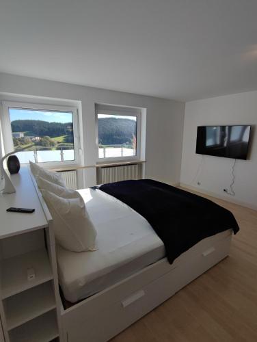 a bedroom with a bed with a desk and a television at Ferienhaus Alpenblick in Ermengerst