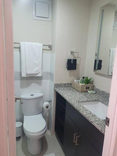 a white bathroom with a toilet and a sink at Bayfront BlueDream Luxurious 1Bed, 1Ba Apt in Portmore