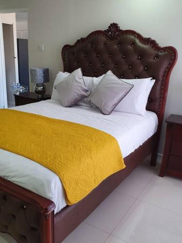 a bedroom with a large bed with a yellow blanket at Bayfront BlueDream Luxurious 1Bed, 1Ba Apt in Portmore