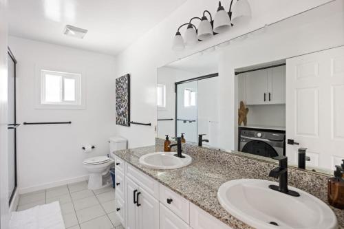 a white bathroom with two sinks and a toilet at Westside Culver Paradise in Los Angeles