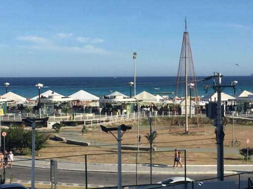 einen Strand mit weißen Sonnenschirmen und dem Meer in der Unterkunft Espaçoso apê 3 quartos à beira da Praia do Forte com piscina e sauna in Cabo Frio