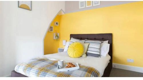 una camera da letto con un grande letto con una parete gialla di Taff Towers snug a Cardiff
