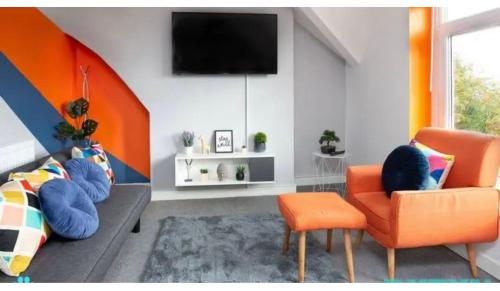 ein Wohnzimmer mit einem orangenen Stuhl und einem TV in der Unterkunft Taff Towers snug in Cardiff