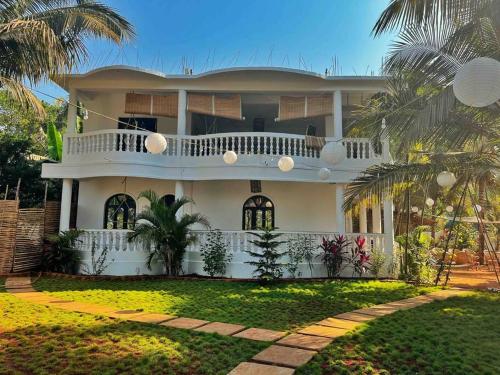 een wit huis met een balkon en palmbomen bij SOLS Backyard in Arambol