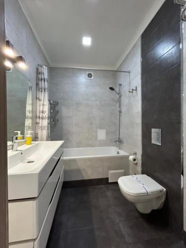 a bathroom with a tub and a toilet and a sink at Kalinova Sloboda Home in Ivano-Frankivsʼk