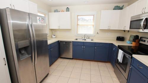 a kitchen with blue cabinets and a stainless steel refrigerator at Oceanside, Private Pool, Hot Tub, Scrn Prch, OS2N, It doesn't get better than this in Corolla