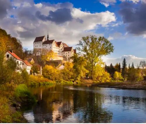 a large building on a hill next to a river at Ferienwohnung am Schloss Colditz in Colditz