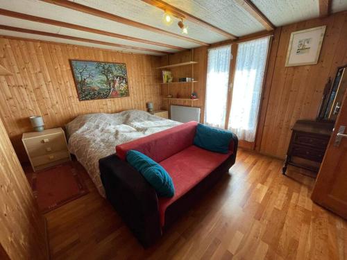 a bedroom with a bed and a red couch at Chalet le Domino - Proche des pistes et des bains in Ovronnaz