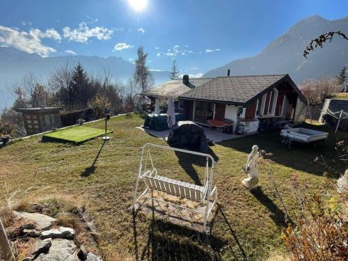 ein Haus mit einem Hof mit einer Bank davor in der Unterkunft Chalet le Domino - Proche des pistes et des bains in Ovronnaz