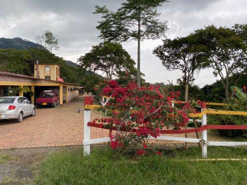 una recinzione con fiori rossi di fronte a un edificio di DinoAgro Potrero Grande a Moniquirá