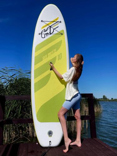 a woman is standing next to a surfboard at VIP ШАЛЕ ТИША in Shirokaya Greblya