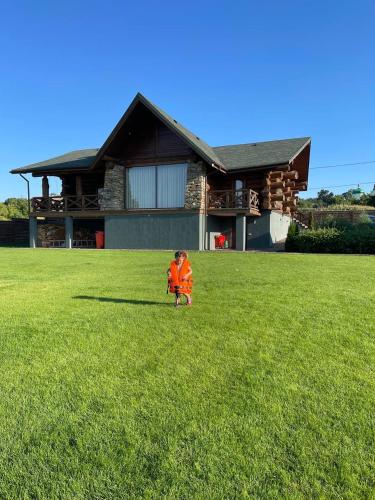 a child standing in a field in front of a house at VIP ШАЛЕ ТИША in Shirokaya Greblya