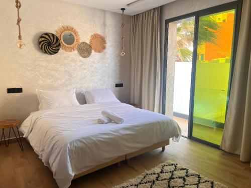 a bedroom with a white bed and a large window at Beach Side Imsouane in Imsouane