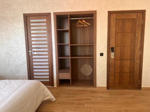 a bedroom with a bed and a closet with wooden doors at Beach Side Imsouane in Imsouane