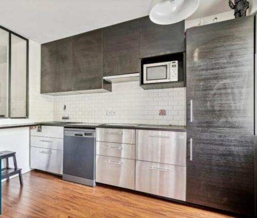 a kitchen with stainless steel appliances and a microwave at Paris : Appartement familial avec parking privé in Clichy
