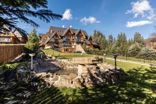 a large log home with a fountain in the yard at Mountain Base - Rezydencja Górski Potok Premium in Kościelisko