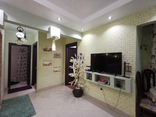 a living room with a television on a brick wall at 2 bedroom, 4 beds, apartment in El sheikh Zayed Cairo Egypt in Sheikh Zayed
