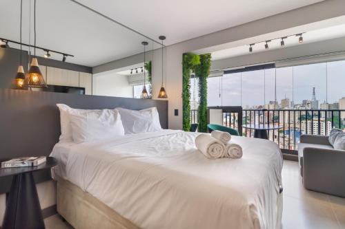 1 dormitorio con 1 cama blanca grande y toallas. en 360 Suítes Facto Paulista - Apartamentos mobiliados, en São Paulo