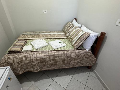 a small bed with two pillows and towels on it at Quarto Laurinda 3 in Guararema