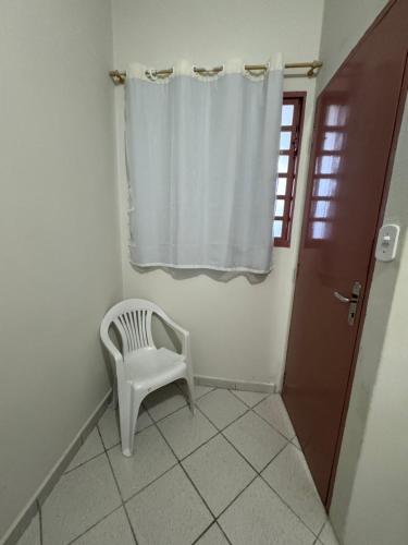 a white chair in a room with a window at Quarto Laurinda 3 in Guararema