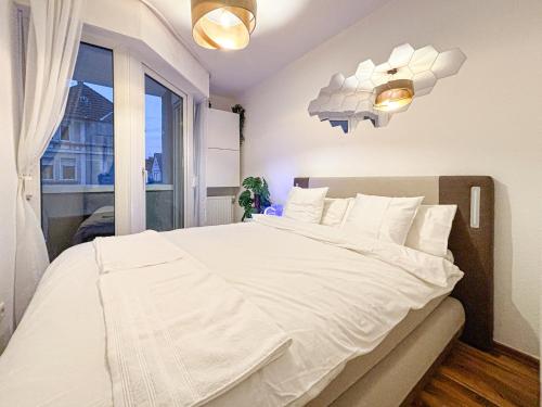 a bedroom with a large white bed with a window at Luxurious Apartment in City-Center with Balcony, Free Parking in Bielefeld