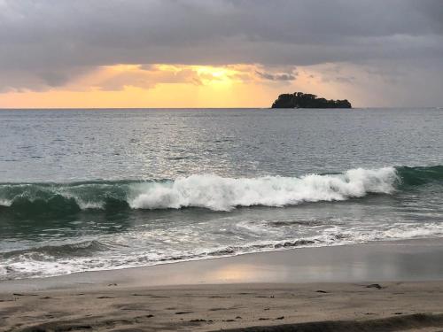 a beach with waves and an island in the ocean at Playa Flamingo - 2 BR condo with great ocean views - FLAMINGO TOWERS 25 in Playa Flamingo