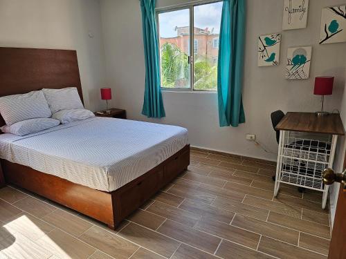 a bedroom with a bed with blue curtains and a window at Amplio Departamento in Cancún