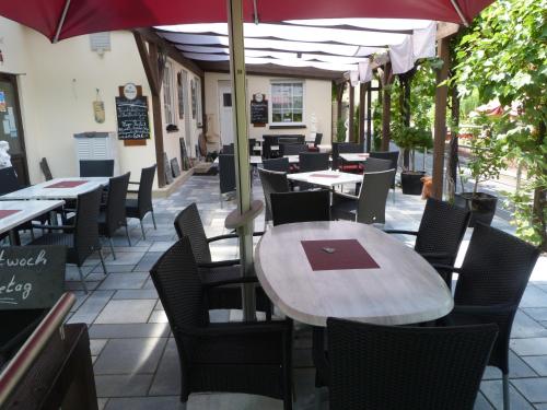 ein Restaurant mit Tischen, Stühlen und einem Sonnenschirm in der Unterkunft Moselperle Hotel Garni in Wolf