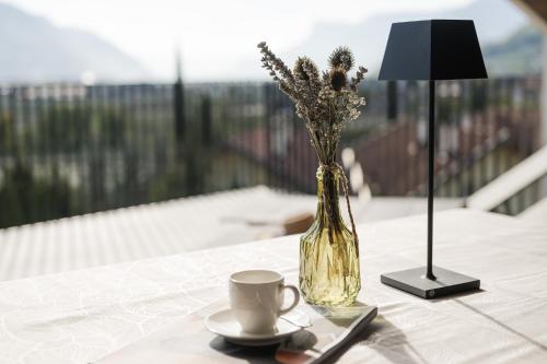 a vase of flowers and a cup of coffee on a table at Apartsuites Rosengarten in Lagundo
