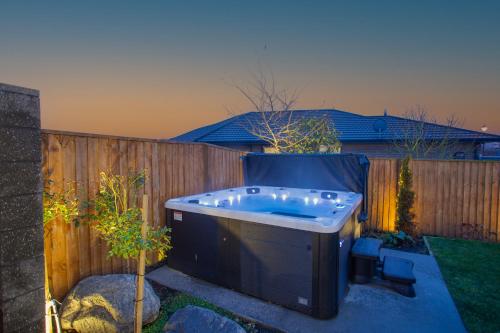 uma banheira de hidromassagem num quintal com uma cerca em Luxury Spa, Outdoor Fireplace & Games Room - Sleeps 10, 18 mins from CHC Airport em Prebbleton