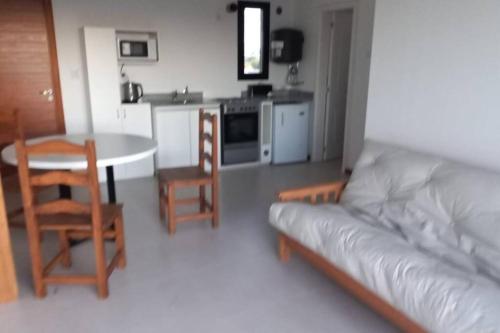 ein Wohnzimmer mit einem Sofa und einem Tisch sowie eine Küche in der Unterkunft Espectacular departamento con inigualables vistas in Balcarce
